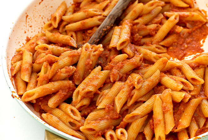 pasta with vodka sauce in saute pan with a wooden spoon.